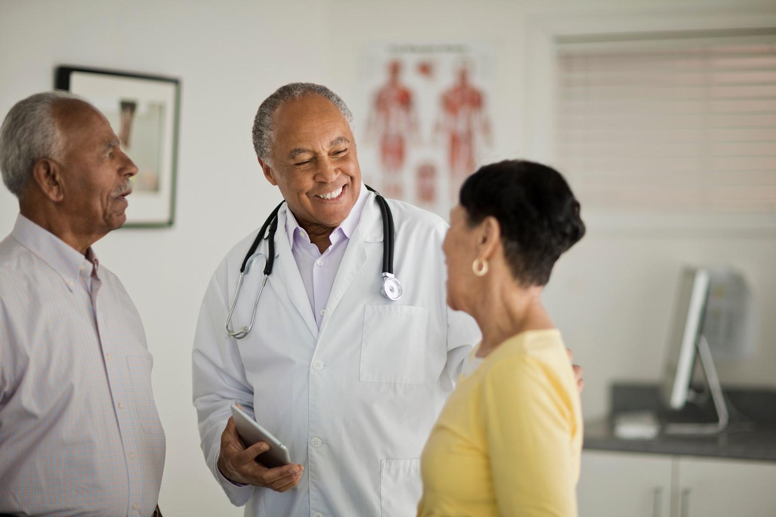 Doctor sonriendo mientras habla con un par de pacientes