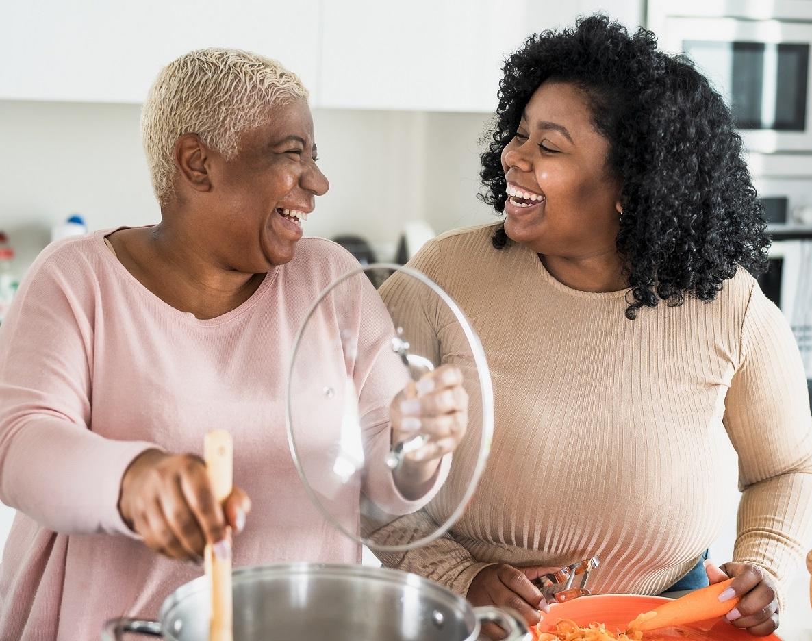 Mãe e filha sorrindo enquanto cozinham juntas